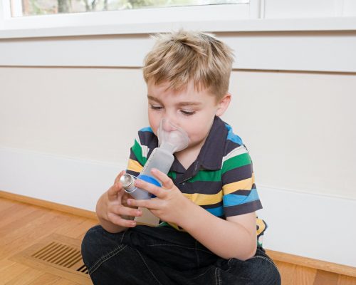 Boy using asthma inhaler with spacer